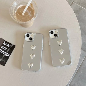 Detail view of silver mirror phone case with three 3D hearts and transparent edges