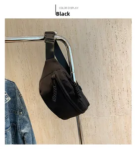 Detail of black nylon chest bag showing zipper pulls and adjustable shoulder strap texture