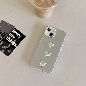 Detail of transparent iPhone case featuring three silver 3D heart-shaped mirrors on back