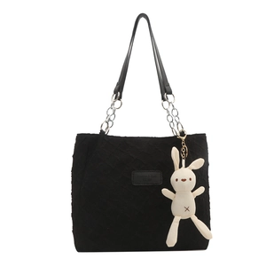 Black quilted tote bag with chain strap and plush bunny charm on white background
