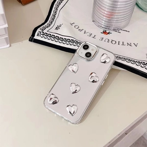 Gros plan d'une coque iPhone miroir argent avec cœurs 3D métalliques sur une table