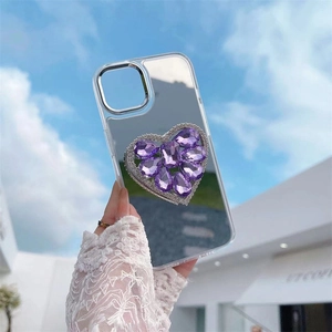 Mirror phone case for iPhone with a purple crystal heart grip against a blue sky background
