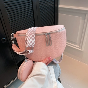 Pink saddle crossbody bag with textured leather and geometric wide woven shoulder strap