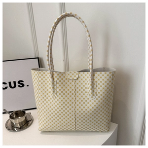 Détail d'un sac cabas blanc avec motif géométrique jaune sur un présentoir épuré