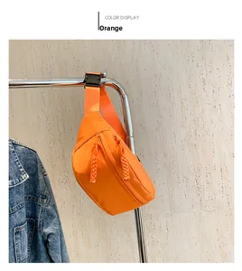 Detail view of an orange nylon chest bag with a woven zipper pull and adjustable strap
