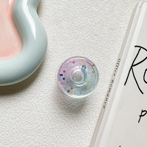 Detailed macro view of a purple gradient star glitter resin phone grip on a white surface