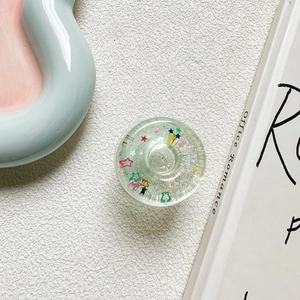 Macro shot of circular phone socket with colorful star sequins in clear resin
