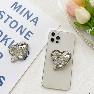 Detail of luxury rhinestone heart phone grip with sparkling crystals and bow pendant