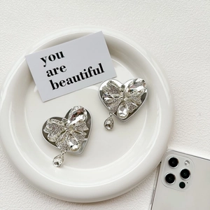 Macro detail of rhinestone bow heart phone stand with teardrop crystals on ceramic plate