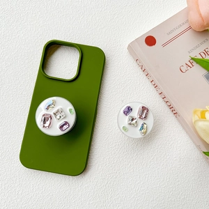 Custodia iPhone verde oliva con supporto cuore in cristallo su sfondo bianco strutturato