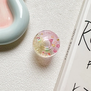 Macro view of a round pink resin phone socket stand filled with colorful star glitters