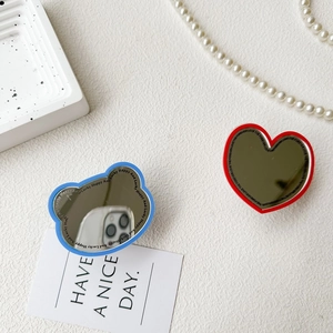 Detail of blue bear and red heart folding mirror phone sockets on aesthetic background