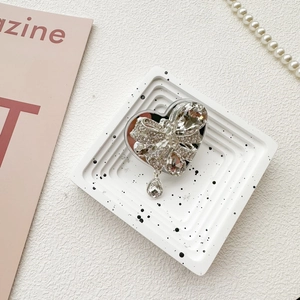 Detail of luxury heart-shaped phone grip with rhinestone bow and sparkling pear pendant