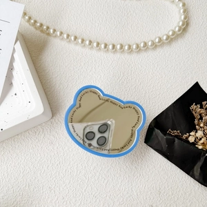 Detail of blue bear-shaped foldable phone grip mirror with 'Lucky Happy' text on white background