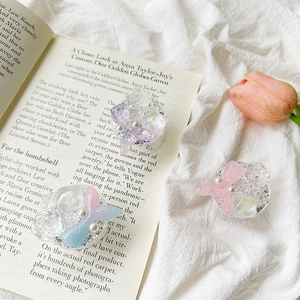 Detail of floral sequin pearl phone grips with mermaid tail design on a book background