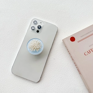 Elegant phone grip with white pearls on a light blue base over a minimalist background