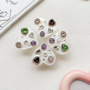 Detail of four heart-shaped phone grips with colorful rhinestones on a white background