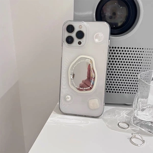 Detail of white iPhone case with irregular silver mirror and pearl accent on white desk