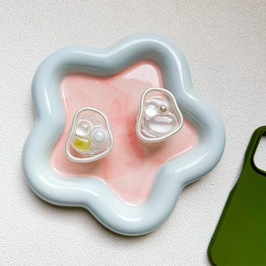 Detail of a resin phone grip cap with pearls and green stones on a ceramic tray