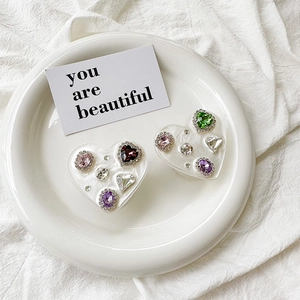 Detailed close-up of heart-shaped phone grips with colorful rhinestones on a white plate