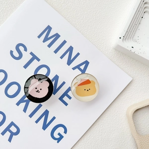 Detail of two decorative glass phone grips with cute bear patterns on a minimalist book