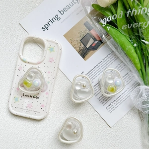 Flat lay of white ink-splatter phone case with three pearl and gemstone air cushion grips
