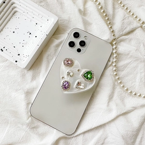 Close-up of heart-shaped phone grip with colorful rhinestones on a white smartphone