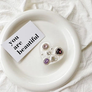 Macro detail of heart-shaped phone socket with colorful rhinestones on white ceramic plate