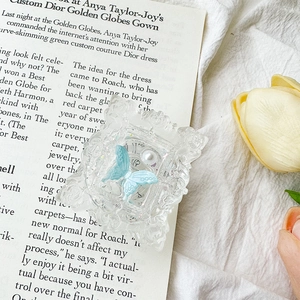 Detail of floral embossed clear phone grip with blue butterfly and pearl accent