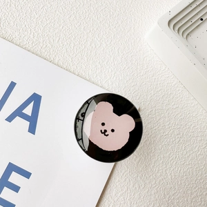 Macro shot of circular phone grip with black mirror surface and cute pink bear illustration