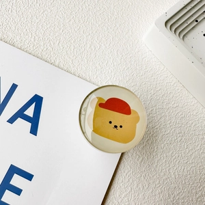 Detail of round crystal resin phone grip featuring a cute yellow bear with a red hat