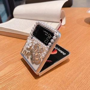 Detail of luxury Samsung Z Flip case featuring white pearls, gold crown and floral accents