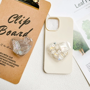Cream silicone phone case with butterfly heart airbag stand on vintage desk setup