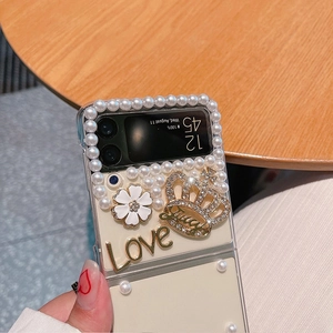 Close-up of pearl beads and a gold rhinestone crown on a white Samsung Z Flip case