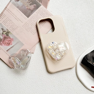 Detailed close-up of heart-shaped resin phone stand with pearls and glitter on leather case
