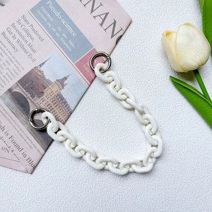 Close-up of a white acrylic chunky chain strap with silver metal rings on a floral background