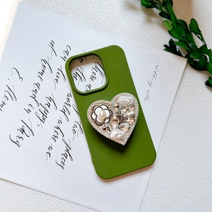 Macro shot of green heart phone grip with pearl camellia flower and rhinestone bee charms
