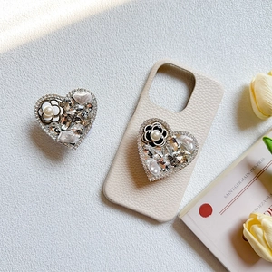Detail of luxury camellia pearl heart phone grip on beige lychee leather case