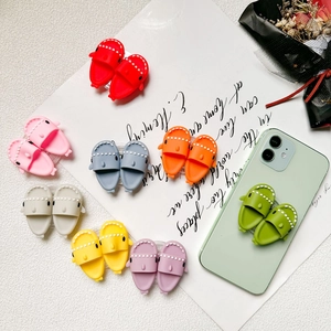 Variety of cute silicone shark slipper phone grips in multiple vibrant colors on a desk