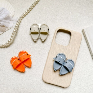 Detail of 3D shark slipper phone sockets in orange, blue, and beige with leather case
