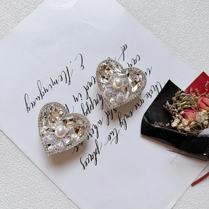 Close-up of luxury heart phone sockets with rhinestones and pearls on a white paper