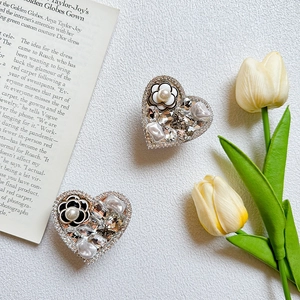 Detailed view of heart-shaped grips with camellia, pearls and crystals on stone background