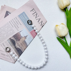 Close-up of elegant pearl chain strap with silver ring clasps on white background