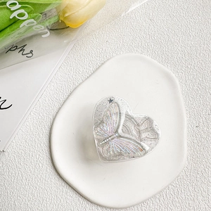 Detail of heart-shaped glitter phone grip with 3D laser butterfly in ceramic tray