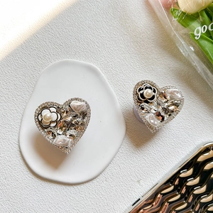 Macro detail of heart-shaped phone grip with luxury rhinestones, pearls and camellia