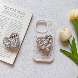 Close-up of luxury heart phone grip with sparkling rhinestones and white pearl inlay