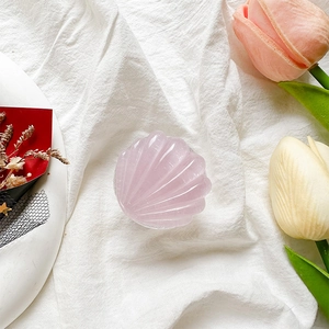 Detailed close-up of a pink seashell phone grip on white textured fabric background