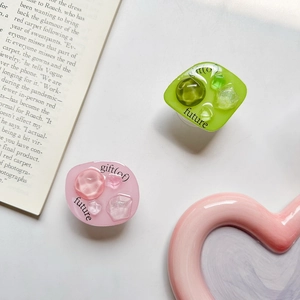 Close-up of green and pink resin phone griptoks with gemstone textures and engravings