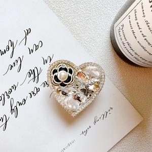 Macro detail of heart-shaped luxury phone grip with camellia, pearls and rhinestones