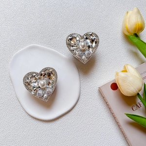 Detail of luxury heart-shaped phone grip with sparkling rhinestones and white pearls